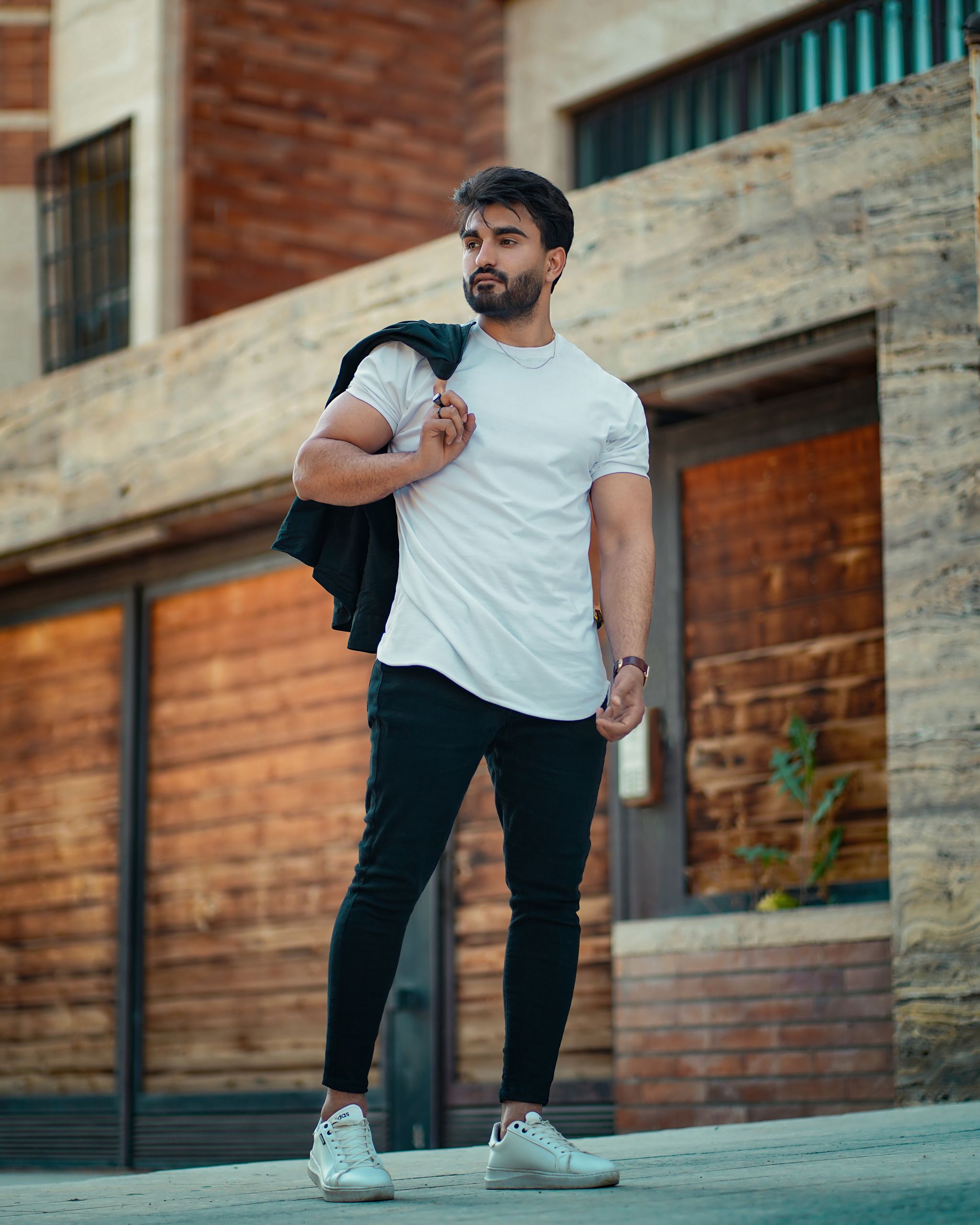 Stylish man in a white t-shirt and black pants posing outdoors in Shush, Khuzestan Province, Iran.